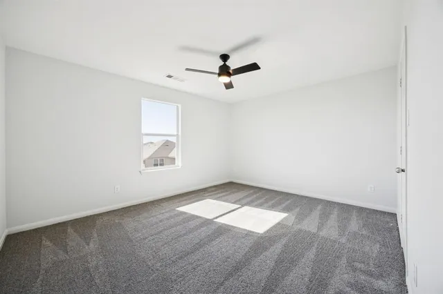 an empty room with windows and fan