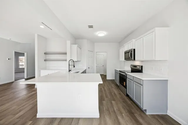 a large white kitchen with wooden floor