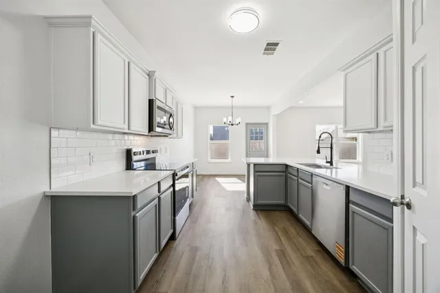 a kitchen with granite countertop a sink stove refrigerator and cabinets