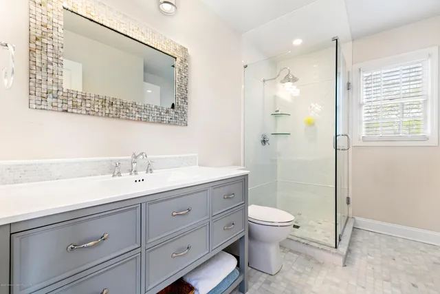 a bathroom with a granite countertop sink a toilet and a mirror