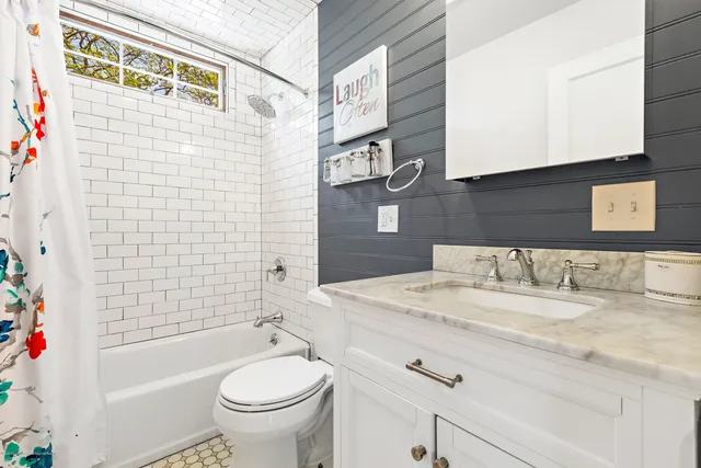 a bathroom with a granite countertop bathtub sink vanity mirror and toilet