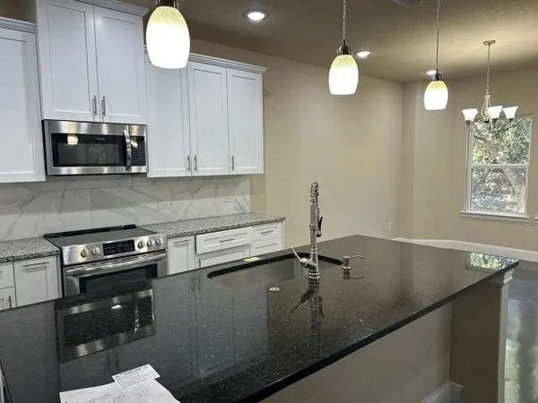 a kitchen with granite countertop a sink a stove and cabinets