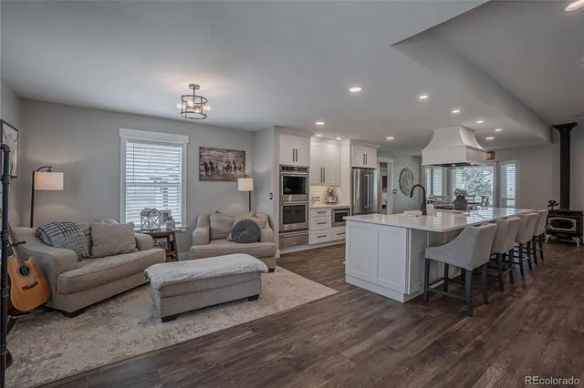 a living room with furniture kitchen view and a wooden floor