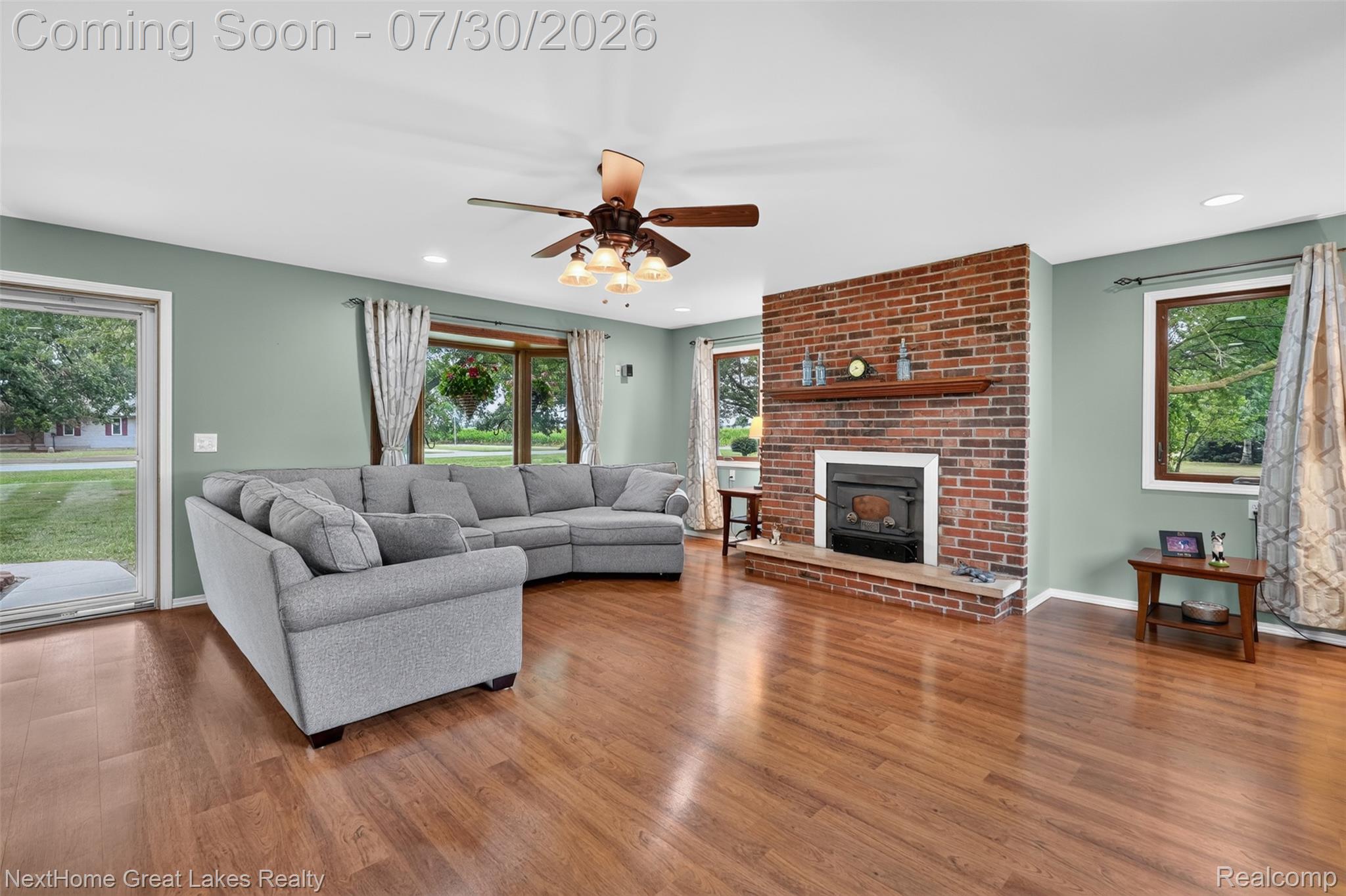 6249 North New Lothrop Road New Lothrop, MI 48460 - Photo 7 of 50 Spacious living area featuring wood-finish flooring, a prominent brick fireplace with a wood mantle and hearth, and recessed lighting