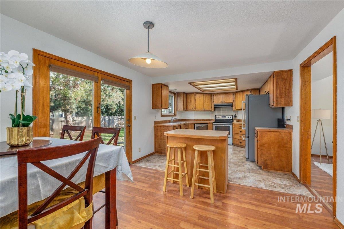 236 East Bayview Court Boise, ID 83706 - Photo 20 of 49 Kitchen with wood finish cabinetry, stainless steel appliances, light countertops, a kitchen bar, and pendant lighting