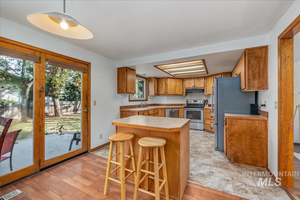 236 East Bayview Court Boise, ID 83706 - Photo 21 of 49 Kitchen with a kitchen breakfast bar, light countertops, wood finish cabinets, stainless steel appliances, and light wood finished floors