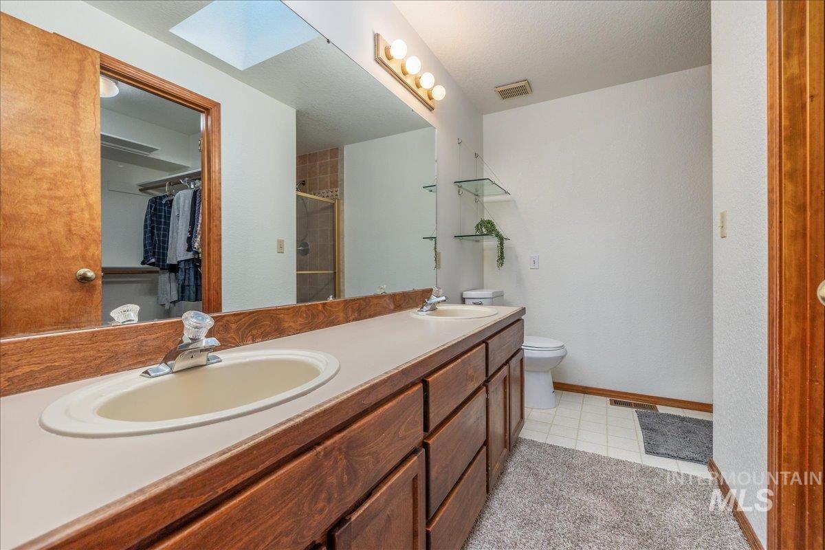 236 East Bayview Court Boise, ID 83706 - Photo 29 of 49 Bathroom with double vanity, a spacious closet, a stall shower, a skylight, and light floors