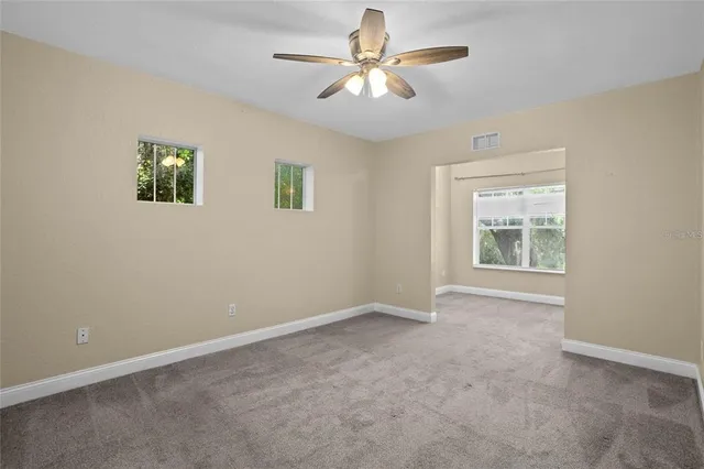 an empty room with windows and fan