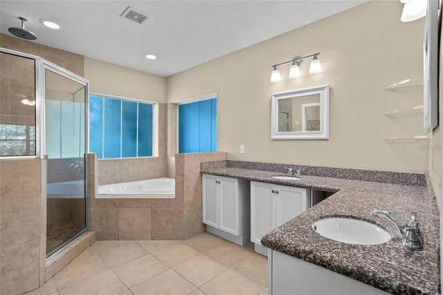 a bathroom with a granite countertop double vanity sink and mirror