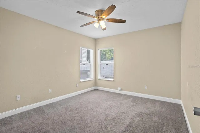 an empty room with window and a ceiling fan
