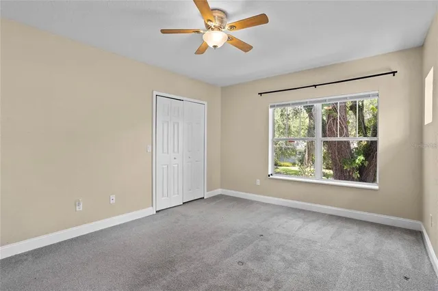an empty room with windows and fan