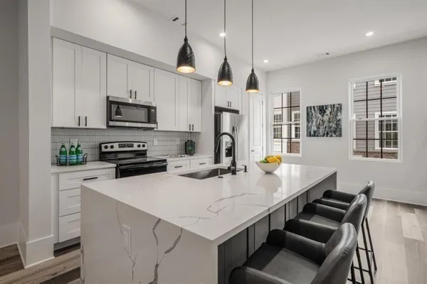 a kitchen with stainless steel appliances a stove a sink a microwave a refrigerator a stove a dining table and chairs