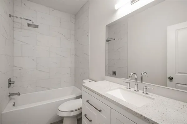 a bathroom with a granite countertop sink a toilet and a bathtub