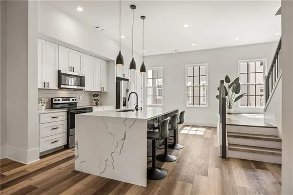 a kitchen with stainless steel appliances a stove top oven a refrigerator a center island and wooden floor