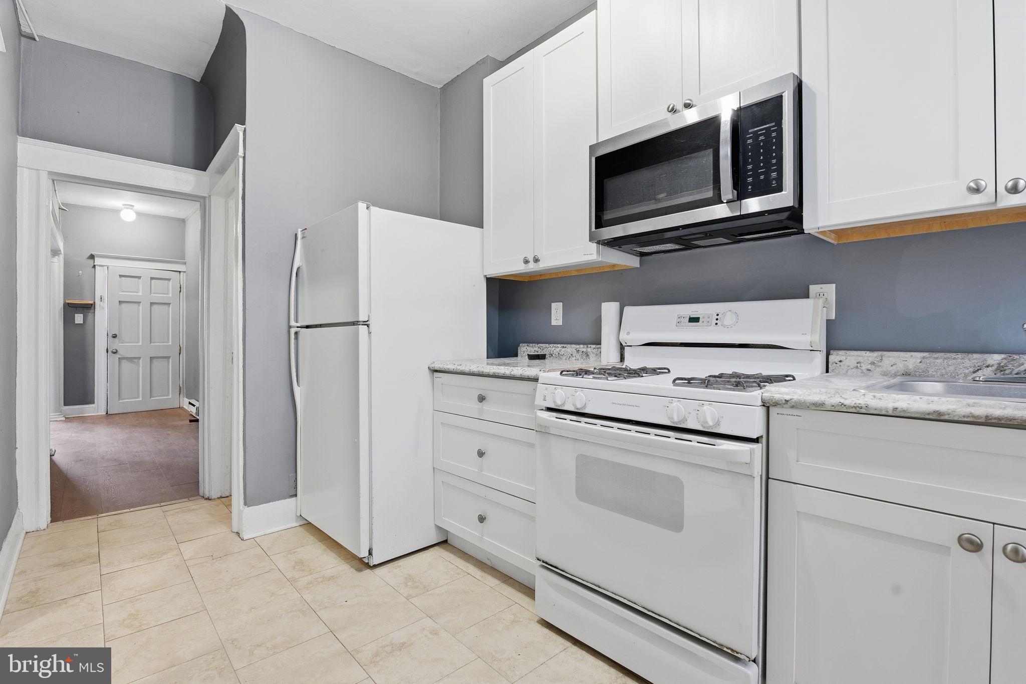 5 South Wickham Road Baltimore, MD 21229 - Photo 7 of 28 a kitchen with granite countertop white cabinets stainless steel appliances and sink