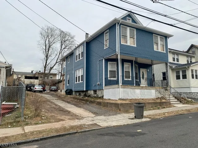 a view of a white house with large windows next to a road