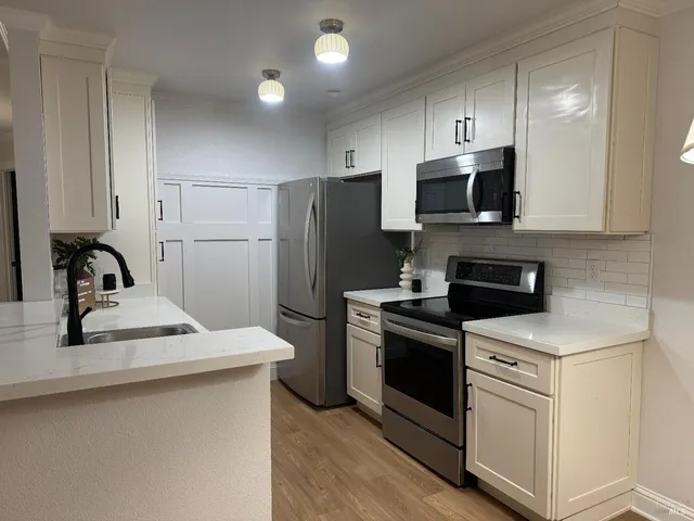 a kitchen with white cabinets stainless steel appliances and sink