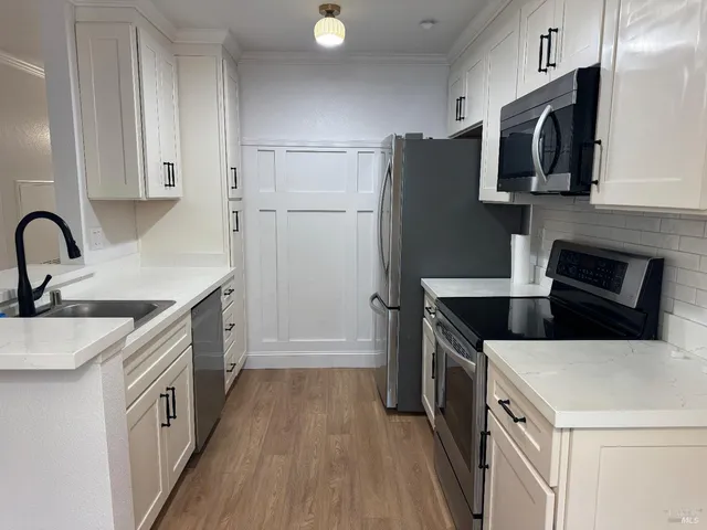 a kitchen with a sink a microwave a refrigerator and cabinets