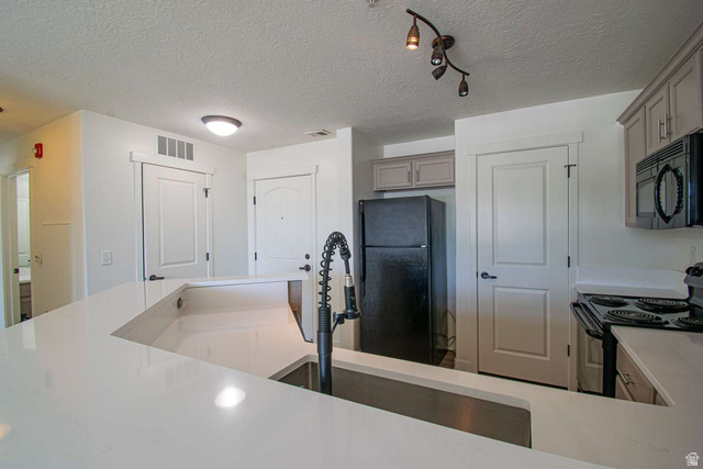 4276 South Main Street, Unit 303 Murray, UT 84107 - Photo 3 of 20 Kitchen showcasing an expansive peninsula with a built-in sink, sleek black appliances, light-toned cabinetry, and recessed lighting