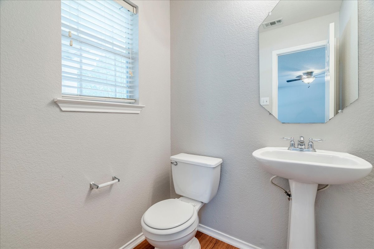 1507 Davis Mountain Loop Cedar Park, TX 78613 - Photo 10 of 30 Downstairs half bath with pedestal sink with chrome faucet hardware, light gray walls with wood laminate flooring