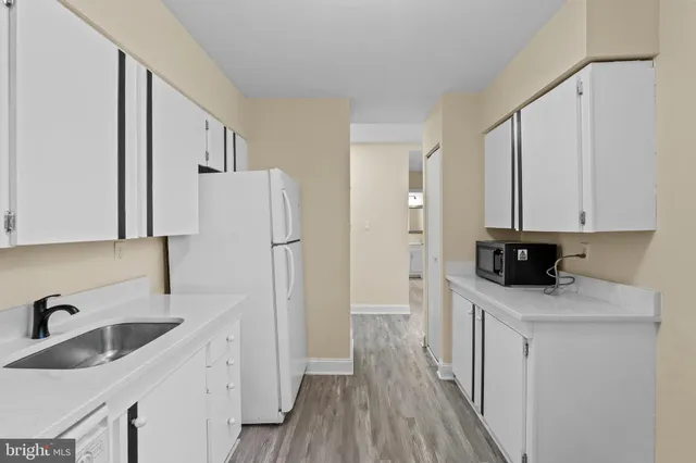 a kitchen with a sink a refrigerator and cabinets
