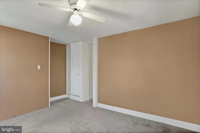 an empty room with closet and a ceiling fan