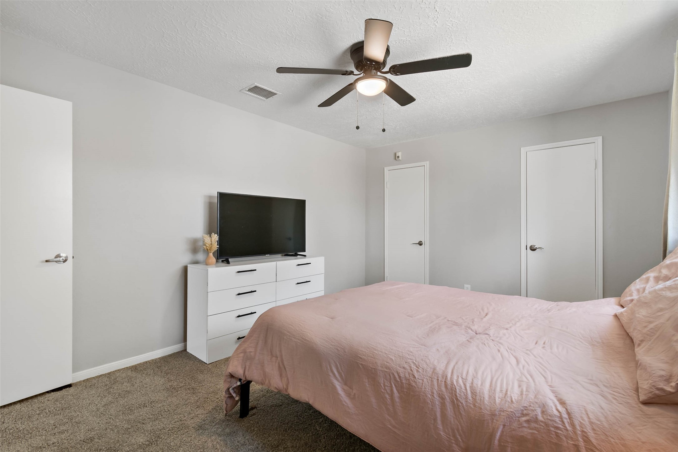 4302 Seneca Street Pasadena, TX 77504 - Photo 12 of 19 a bedroom with a bed a flat screen tv and a ceiling fan