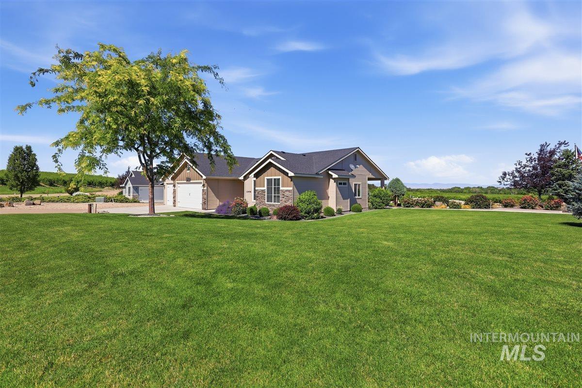 13496 Hockberger Ranch Road Caldwell, ID 83607 - Photo 28 of 40 Expansive green lawn with a single-story residence featuring stucco and stone veneer siding