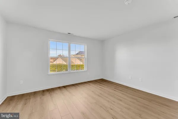 an empty room with a window and wooden floor