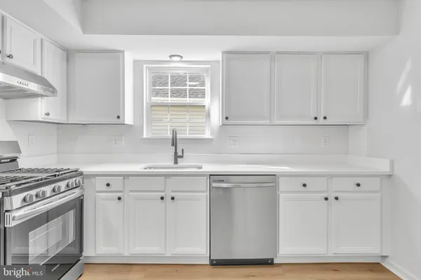 a kitchen with white cabinets and sink