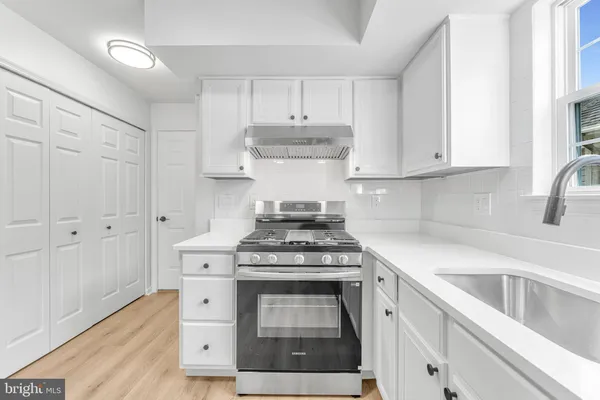 a kitchen with stainless steel appliances granite countertop a stove and white cabinets