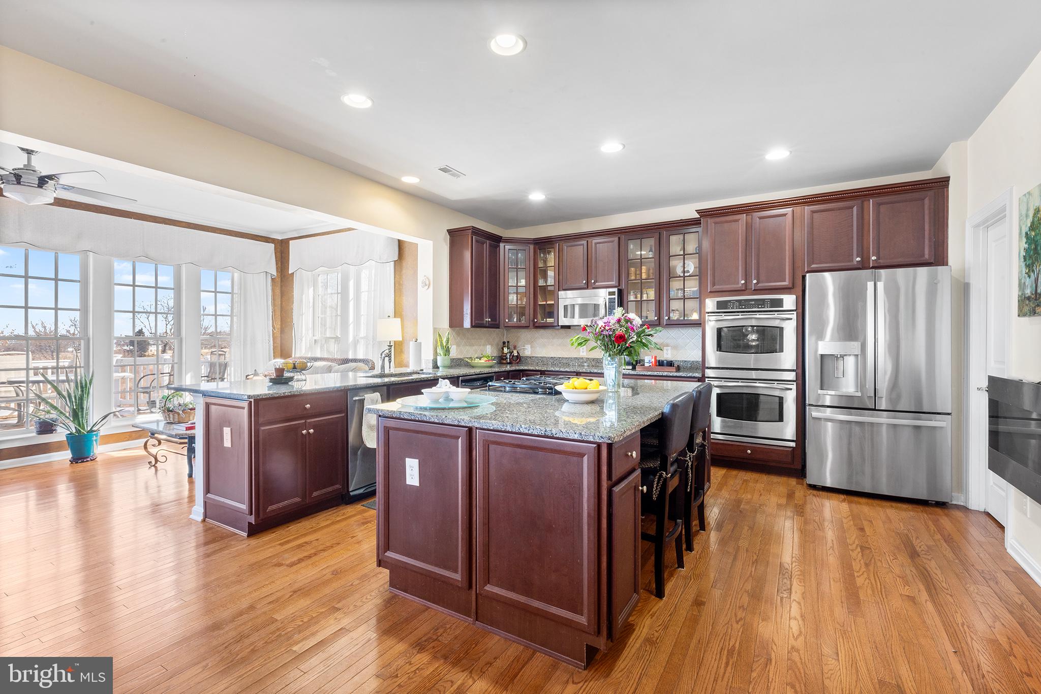 72 Hollow Drive Malvern, PA 19355 - Photo 4 of 63 a kitchen with stainless steel appliances granite countertop a refrigerator a stove top oven a sink dishwasher and a dining table with wooden floor