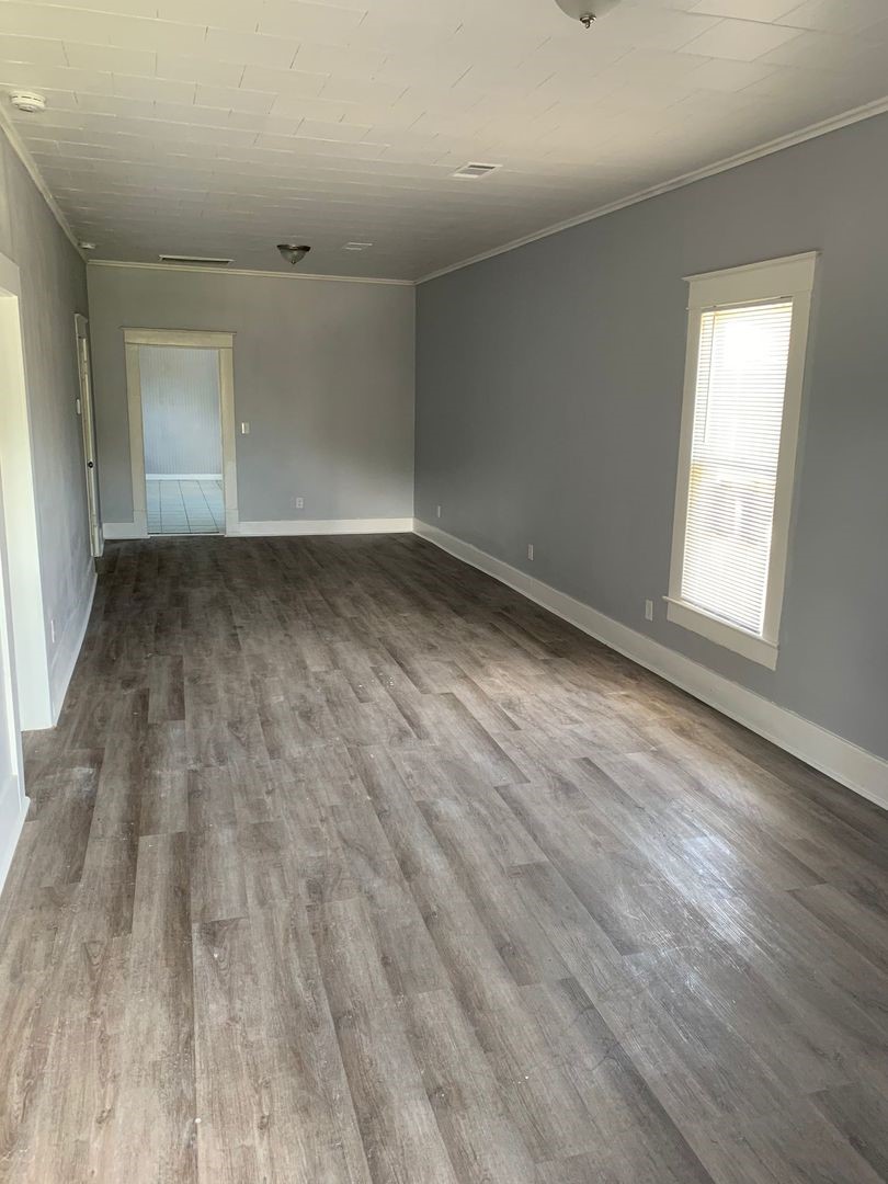 1409 10th Street Port Arthur, TX 77640 - Photo 2 of 11 an empty room with wooden floor and windows