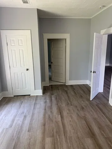 an empty room with wooden floor and closet area