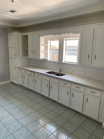 a kitchen with granite countertop a sink and white cabinets