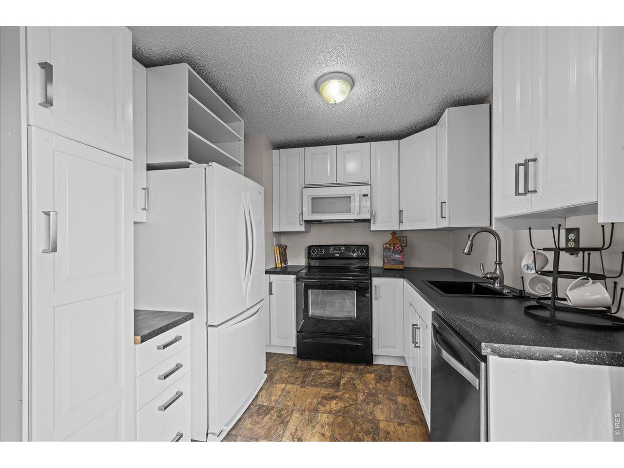 516 West Main Street Pierce, CO 80650 - Photo 7 of 24 a kitchen with granite countertop a refrigerator stove and white cabinets