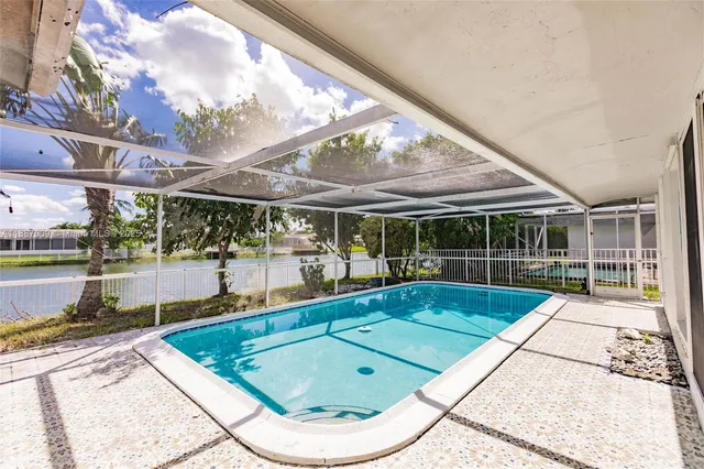 a view of a house with pool and a yard with table and chairs next to a yard