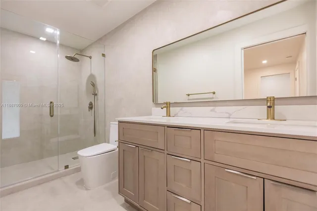 a bathroom with a shower sink vanity mirror and toilet