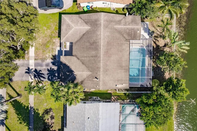 an aerial view of a house with a yard and a large tree