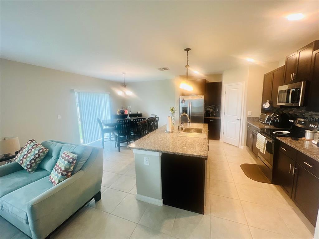 2170 Shining Azul Way Lutz, FL 33558 - Photo 7 of 16 a kitchen with stainless steel appliances kitchen island granite countertop a refrigerator a stove and a sink with wooden floor