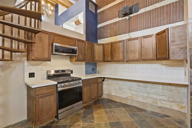 a kitchen with stainless steel appliances granite countertop a stove a sink and a microwave