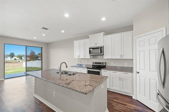 a view of an empty room with wooden floor and a ceiling fan