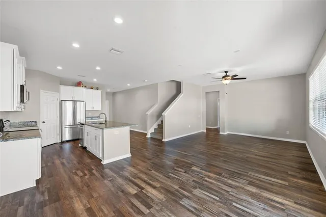 a kitchen with granite countertop a refrigerator a sink a stove a microwave a counter top space and cabinets