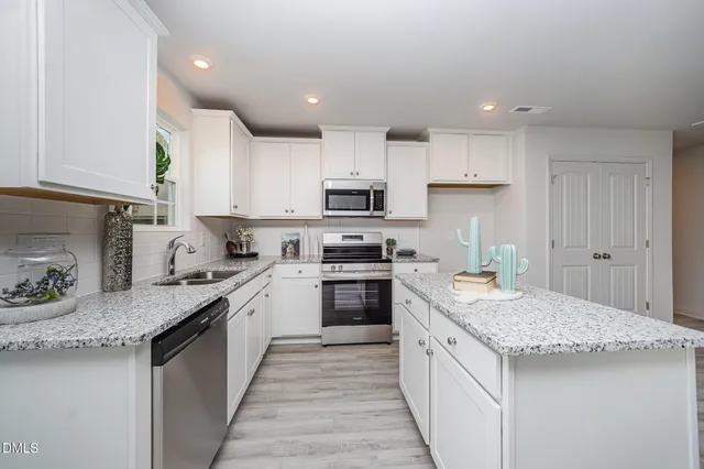 a kitchen with granite countertop kitchen island sink stove and white cabinets