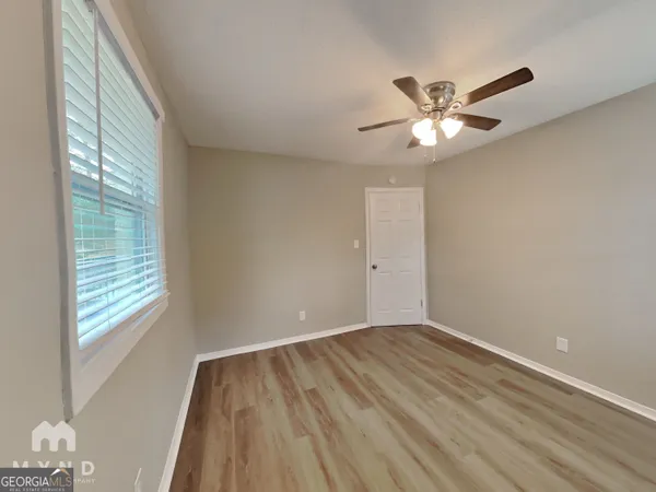 a view of empty room with wooden floor and fan