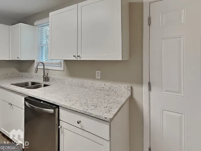 a kitchen with granite countertop white cabinets and a sink