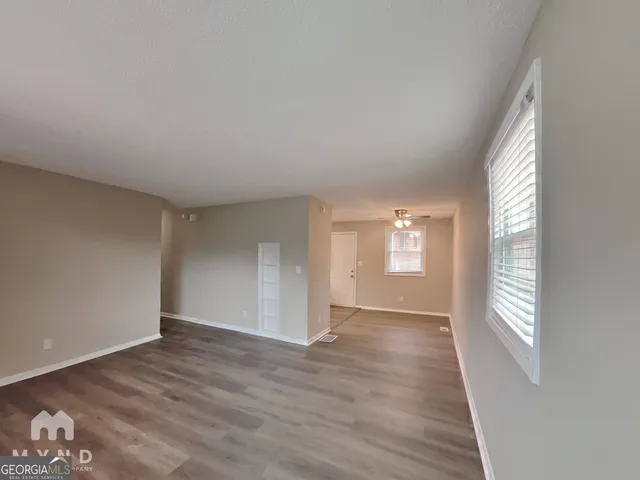 a view of an empty room with wooden floor and a window