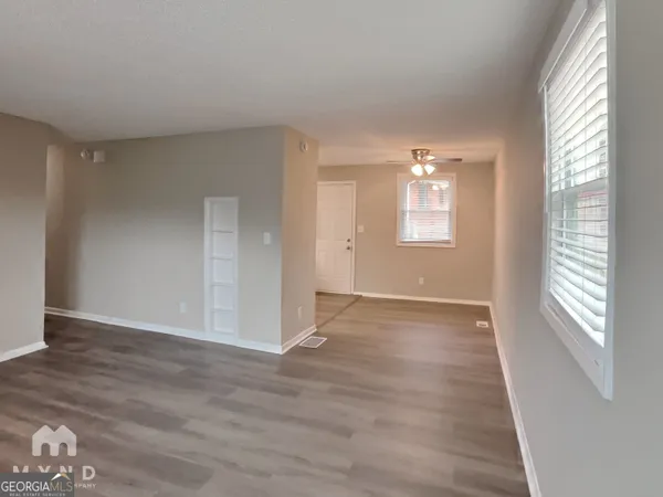 an empty room with wooden floor and windows