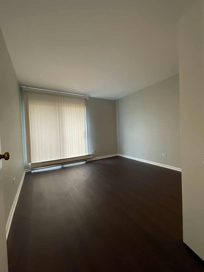 202 South Waters Edge Drive, Unit 201 Glendale Heights, IL 60139 - Photo 10 of 15 an empty room with wooden floor and windows with curtains