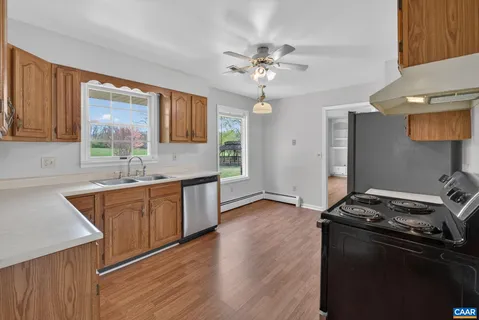 a kitchen with stainless steel appliances granite countertop a sink a stove a refrigerator cabinets and wooden floor
